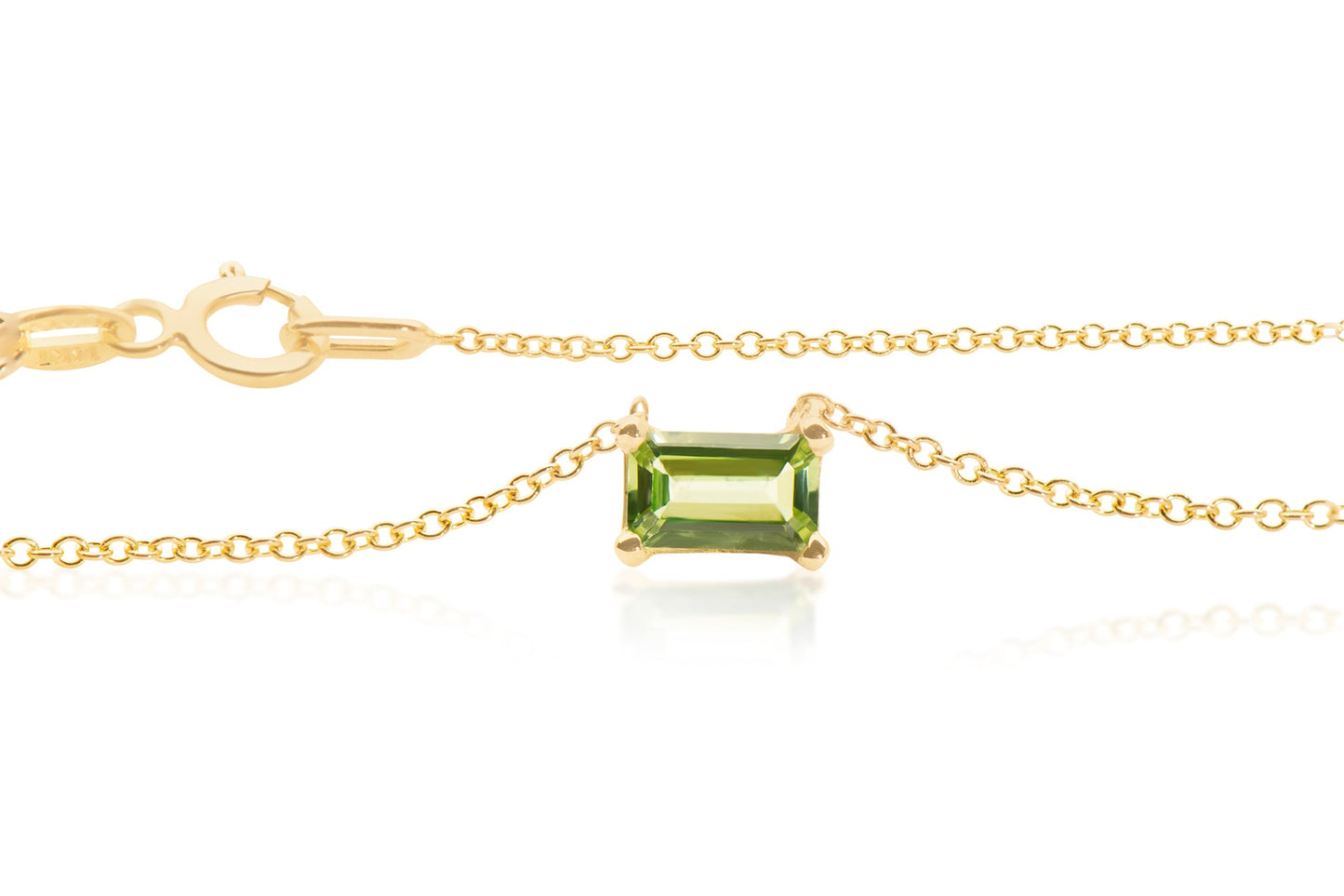 One emerald cut Peridot gemstone set sideways in a 14k yellow gold basket setting with a chain 