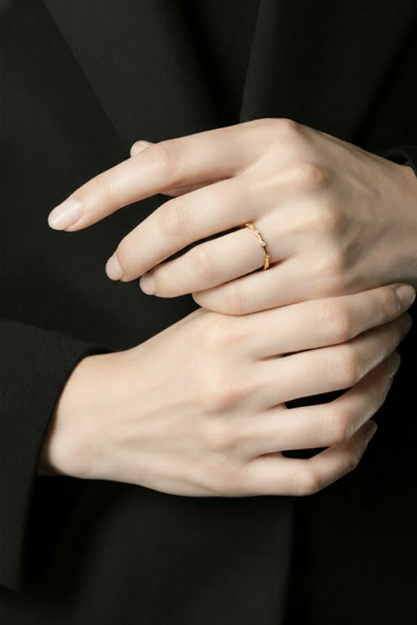 Close-up of hands with a gold ring on a black background