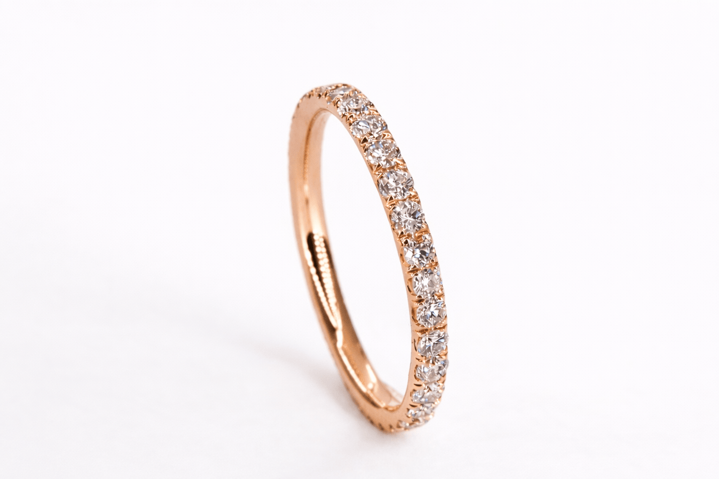 Rose gold ring with small diamonds on a white background