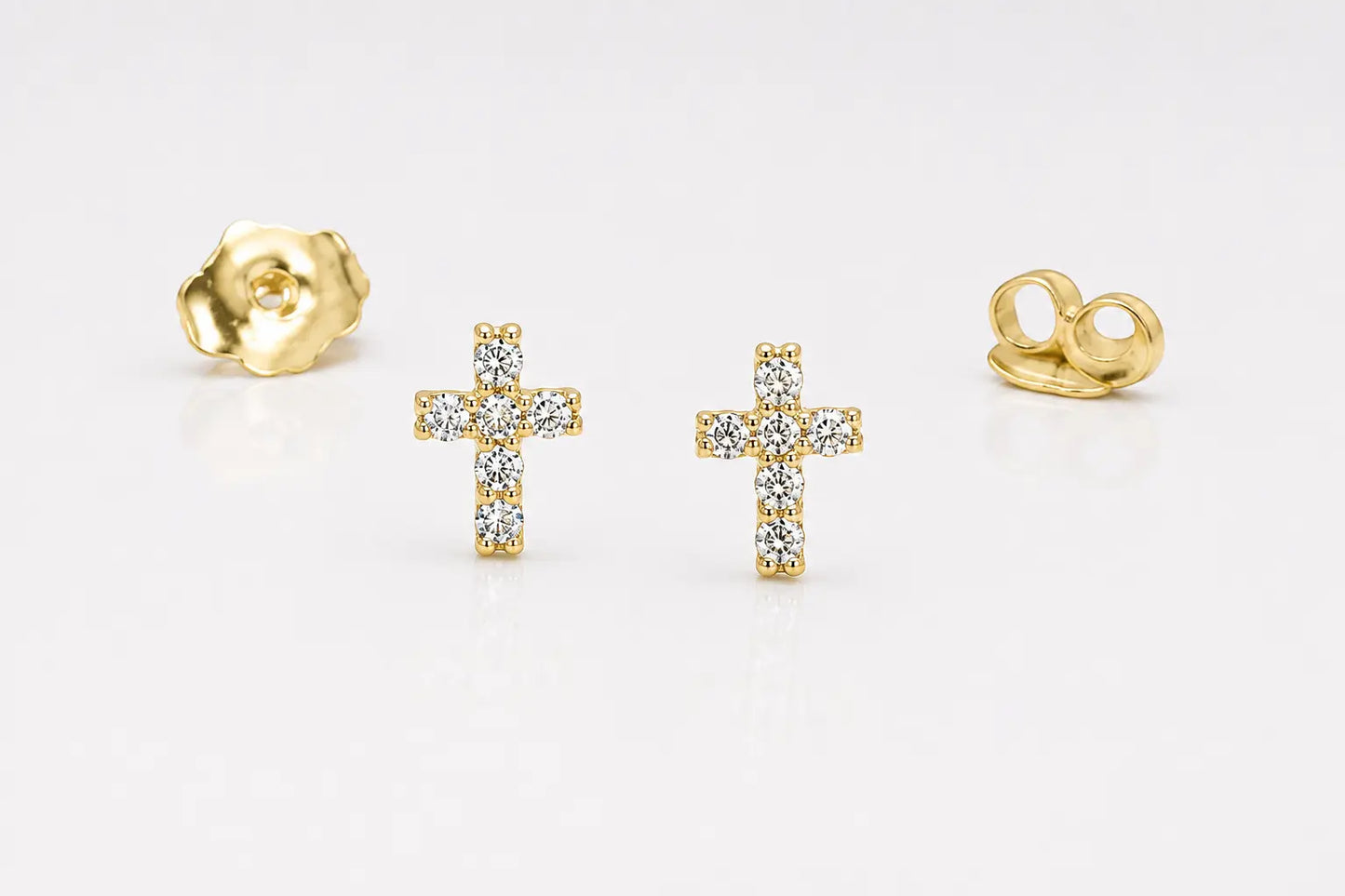 A pair of gold cross stud earrings set with clear stones, shown with their gold backing pieces on a clean white background.