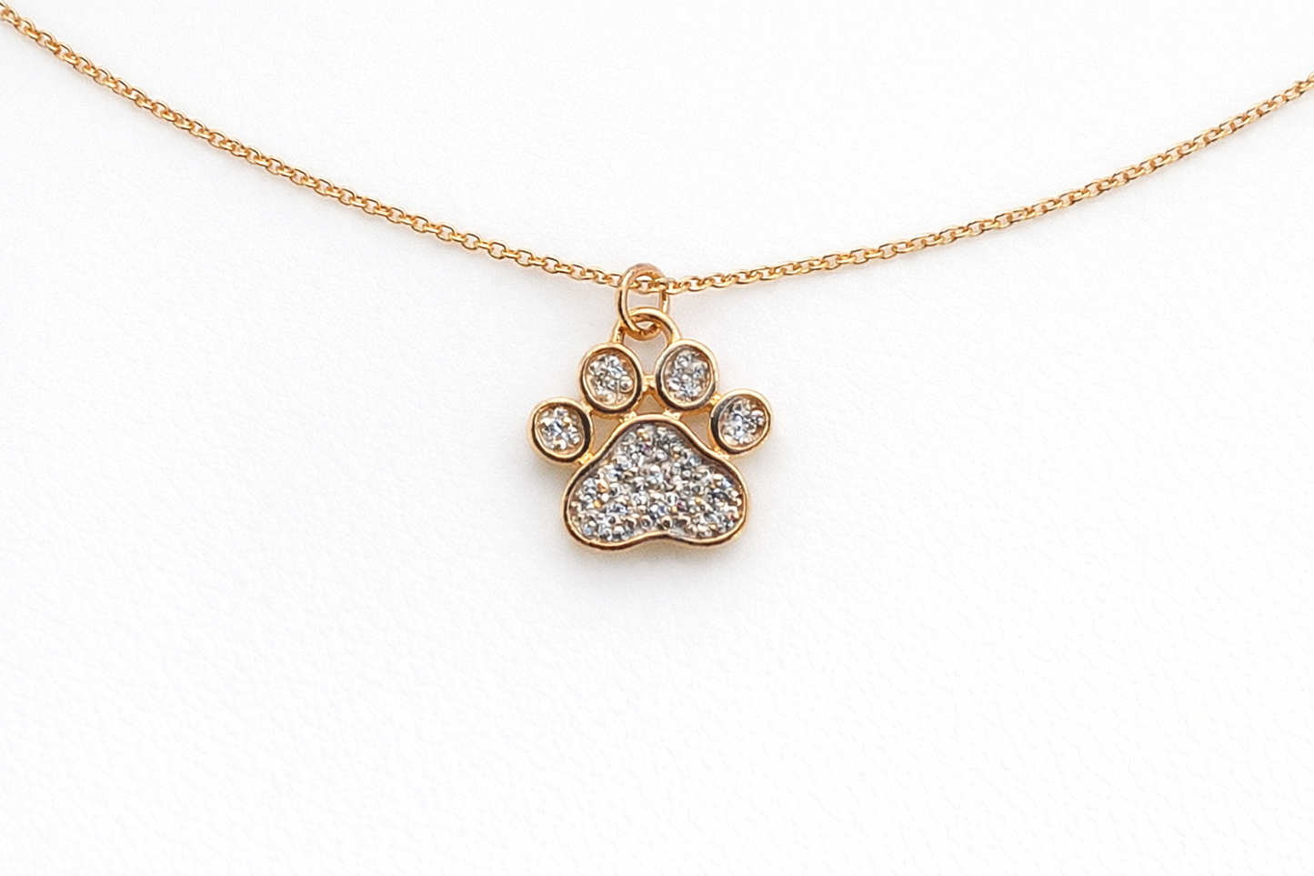 Gold necklace with a paw-shaped pendant on a white background