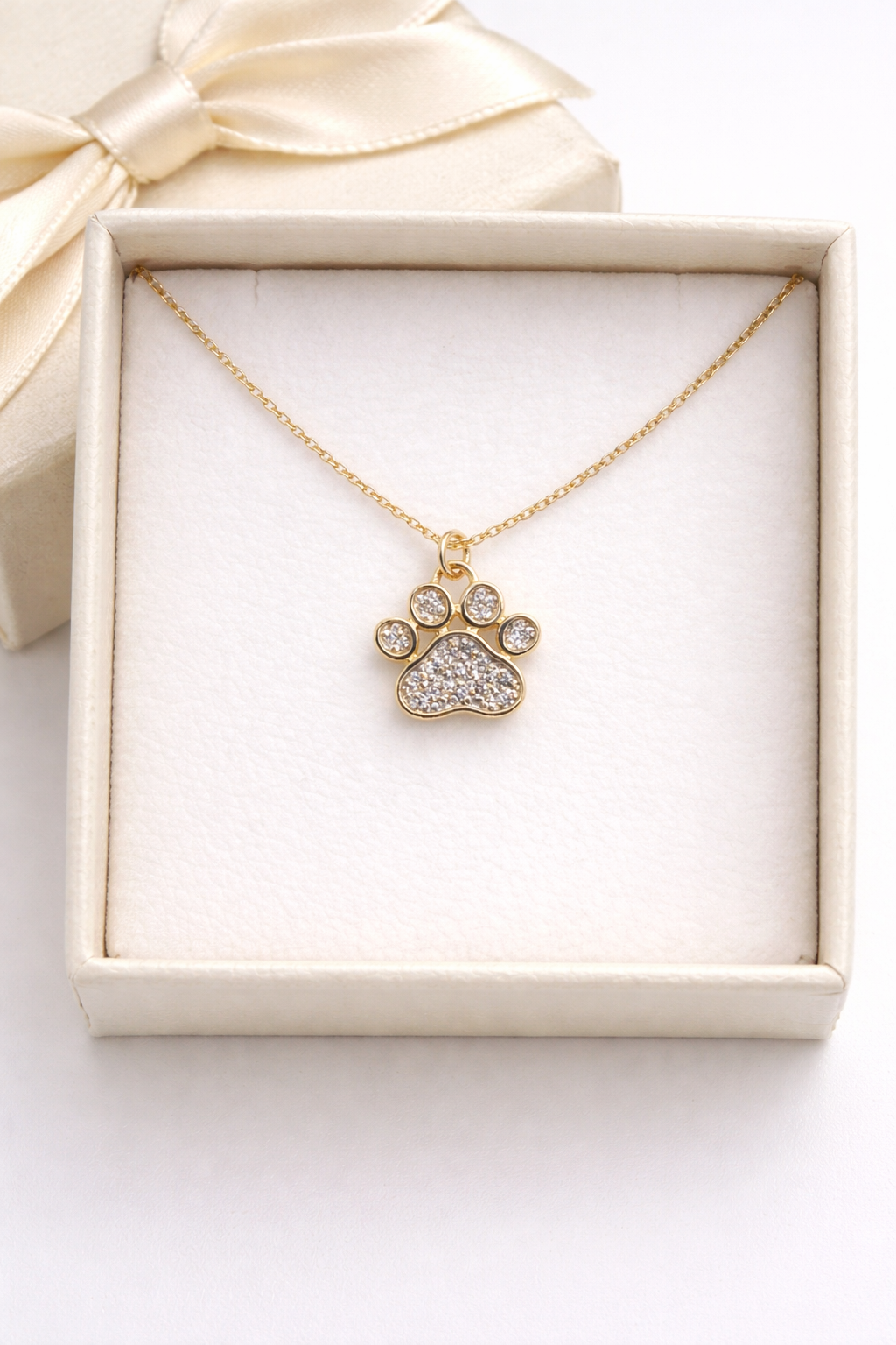 Gold necklace with a paw-shaped pendant in a white box