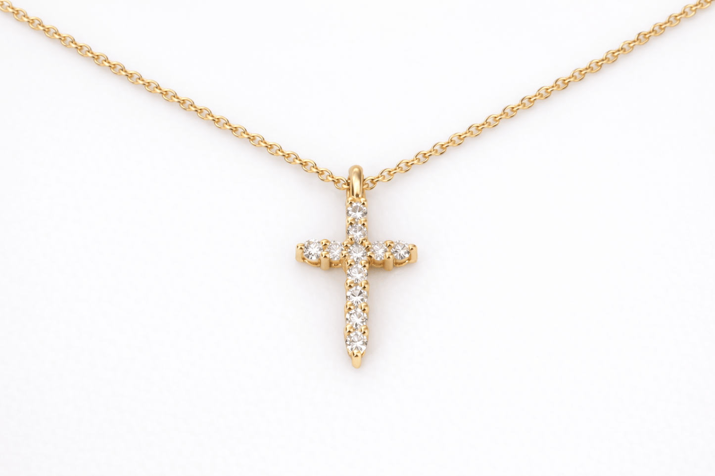 Gold cross necklace with diamonds on a white background